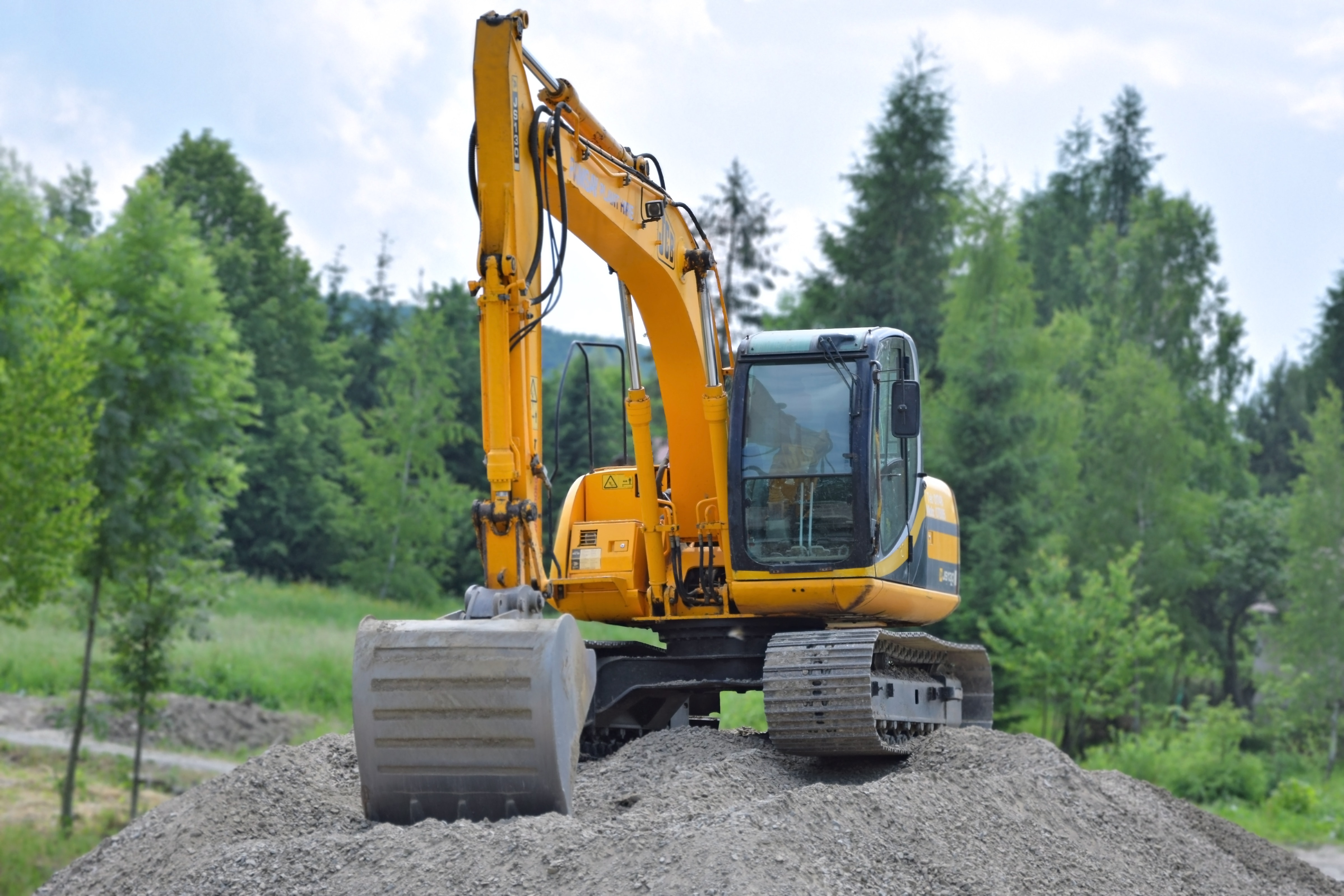 JCB excavator at a construction site with gravel piles